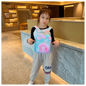 Girl wearing a light blue mermaid print backpack with pink details and side mesh pockets