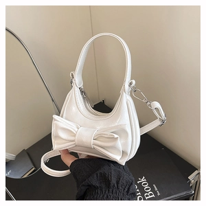 Detail of white bow handbag featuring glossy wrinkled texture and silver metal hardware