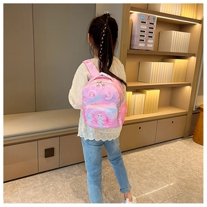 Pink mermaid cartoon backpack for girls shown being worn by a child in a cozy study room
