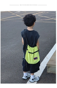 Rear view of a child wearing a vibrant neon green drawstring crossbody bag in street style