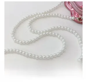 Detail of white faux pearl strap with silver lobster clasp on pink laser crossbody bag
