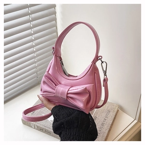 Detail of pink bow shoulder bag with pleated texture and silver hardware accents
