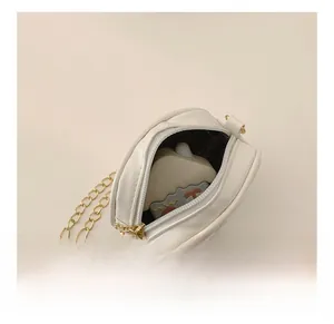 Vista interna di una mini borsa bianca a forma di cuore con catena d'oro e cerniera