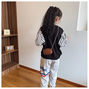 Dettaglio della mini borsa a catena trapuntata a cuore con outfit a righe da bambina