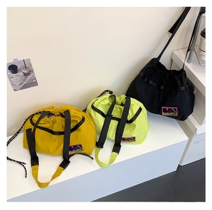 Detailed display of three nylon drawstring crossbody bags in yellow, green, and black colors