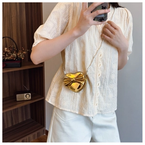 Detail of a heart-shaped gold girl's purse with bow decoration and pearl chain strap