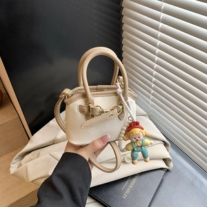Detail of mini canvas crossbody bag with cream leather trim and cute doll charm