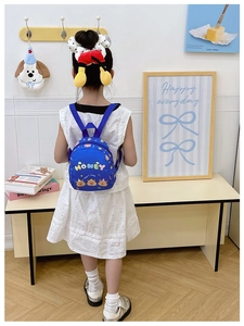 Toddler wearing a cute blue Capybara backpack with colorful Honey letters in a cozy room