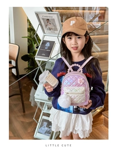 Detail of iridescent pink quilted kids backpack with pearl handle and soft pompom charm