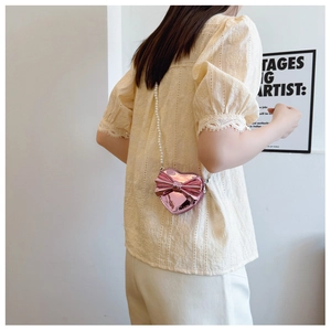 Detail of pink heart crossbody bag for girls with shiny laser finish and pearl chain