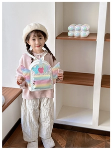 Detail of white quilted kids backpack with unicorn wings and sequin bow decoration