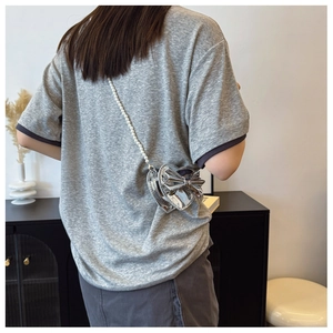 Detail of silver heart-shaped girls bag with oversized bow and pearl chain strap