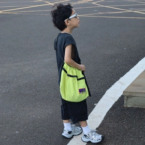 Neon green kids drawstring crossbody bag with stylish geometric patch in outdoor setting