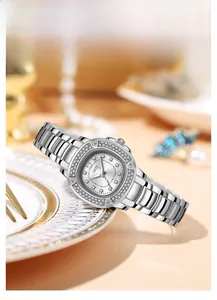 Detail of a luxury silver quartz watch with a crystal-encrusted bezel on a marble surface