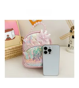 Pink quilted girls backpack with butterfly embroidery and pearl handle shown next to a smartphone