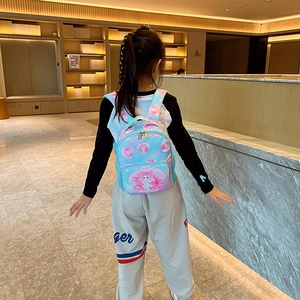 Light blue kids backpack with mermaid print shown on a child model in a cozy room
