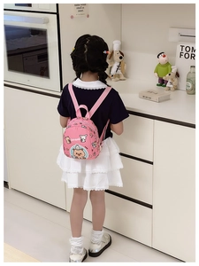 Rear view of a child wearing a pink Capybara cartoon backpack in a cozy kitchen