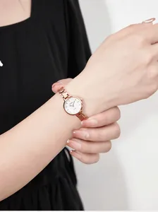 Detailed close-up of a women's rose gold quartz watch with a minimalist white dial