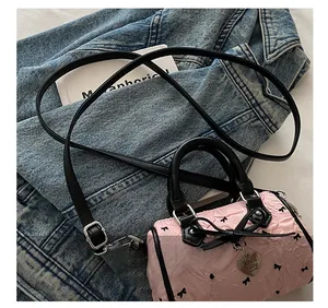 Detail of pink cylinder bag showing the adjustable black strap and metal buckle