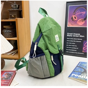 Détail du sac à dos en nylon bicolore avec panneaux verts et bleu marine et logo montagne