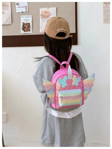 Rear view of a child wearing a pink quilted backpack with rainbow wings and sequin details