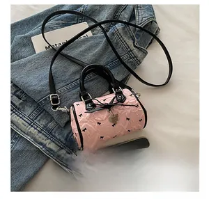 Mini pink crossbody bag for girls with black bow patterns and a heart pendant detail