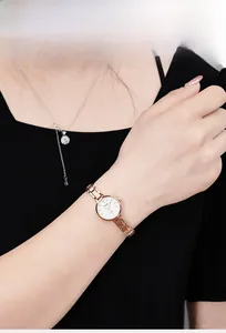 Detail of rose gold quartz watch with elegant link strap and white round dial for women