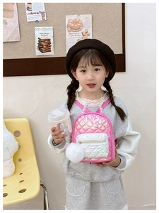 Detailed close-up of quilted pink kids backpack with pearl handle and plush pompom charm