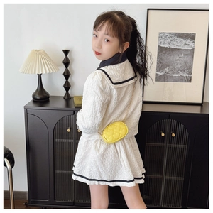 Dettaglio di una mini borsa trapuntata a cuore giallo limone con un completo da bambina