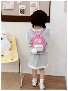 Toddler girl wearing pink quilted backpack with pearl handle and fluffy pom pom charm