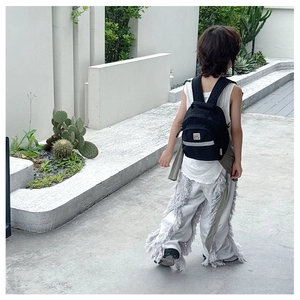 Rear view of a child wearing a black nylon mini backpack with a stylish contrast design