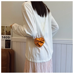 Detail of laser orange heart crossbody bag with pearl strap on child model