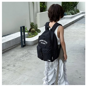 Rear view of child wearing a black school backpack with white letter printing