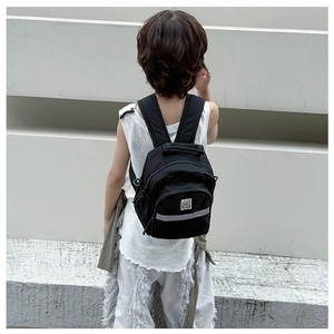 Detail view of black children backpack with safety reflective strip and brand logo