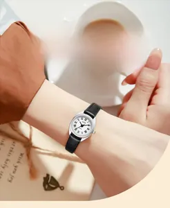 Gros plan d'une petite montre à quartz ovale argentée avec bracelet en cuir noir au poignet