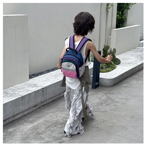 Detail shot of multi-color block kids backpack with purple straps in outdoor minimalist setting