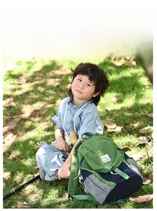 Sac à dos enfant bicolore vert et bleu marine avec patch montagne en scène de plein air