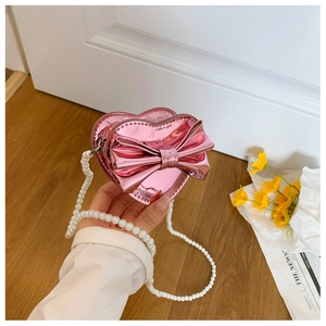 Detail of pink heart-shaped bag with laser mirror finish and white pearl strap