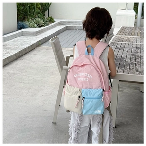 Outdoor view of child wearing a multi-pocket patchwork backpack with adjustable straps