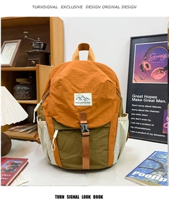 Gros plan détaillé du sac à dos tricolore avec boucles réglables et logo de montagne