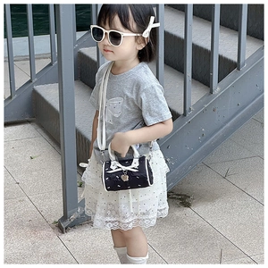 Close-up of a mini girl's crossbody bag with white bow knot and heart-shaped pendant detail