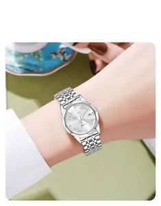 Detail of silver steel watch with diamond markers and date window on woman's wrist