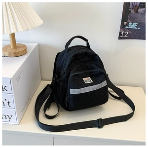 Detail of black mini backpack with reflective safety strip and woven brand label