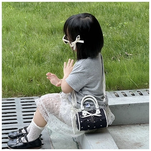 Toddler girl wearing a black bow-knot mini crossbody bag with heart pendant detail