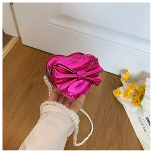 Detail of heart-shaped girls purse with magenta laser surface and pearl chain strap