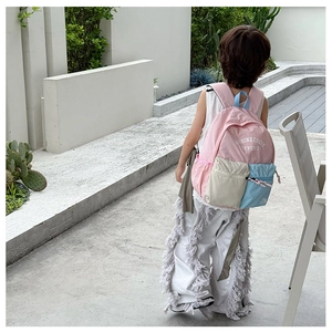 Outdoor shot of a pink and beige color-block kids backpack with SHINE CREEK lettering
