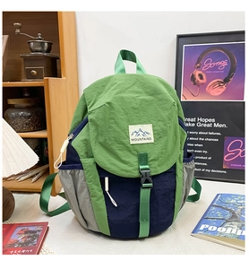 Gros plan du sac à dos en nylon tricolore avec étiquette montagne et boucle de fermeture
