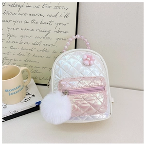Macro view of quilted kids backpack with pearl handle and plush pompom charm