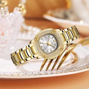 Elegant gold quartz watch for women with sparkling crystal bezel on a golden fork and plate