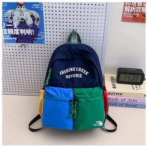 Detail view of colorful multi-pocket nylon backpack with artistic logo and contrast panels